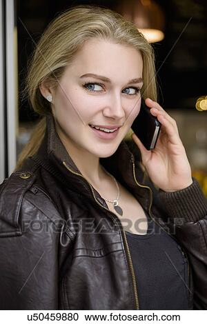 Young woman chatting on smartphone in cafe doorway View Large Photo Image Stock Image - Young woman chatting on smartphone in cafe doorway. Fotosearch