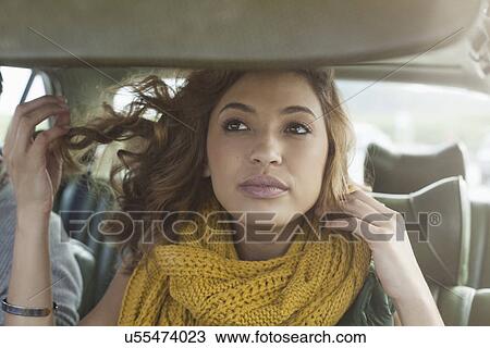 Stock Image - Young woman checking herself in car mirror, Cape Town, Western Cape, South Africa. Fotosearch