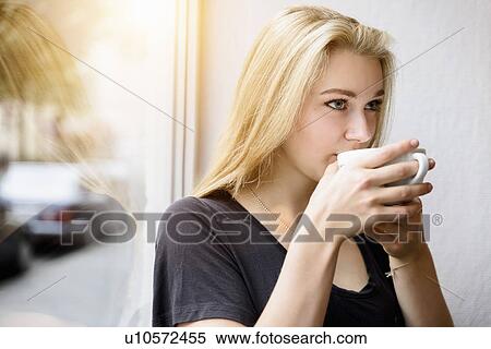 Young woman drinking coffee in window seat View Large Photo Image Stock Photography - Young woman drinking coffee in window seat. Fotosearch