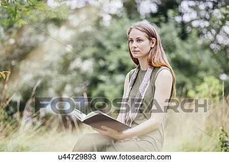 Young woman in field distracted from reading book View Large Photo Image Stock Image - Young woman in field distracted from reading book. Fotosearch