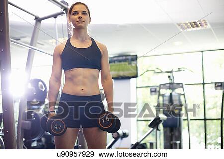 Stock Photo - Young woman lifting hand weights. Fotosearch
