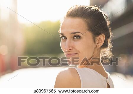 Young woman looking over shoulder towards camera View Large Photo Image Stock Photography - Young woman looking over shoulder towards camera. Fotosearch