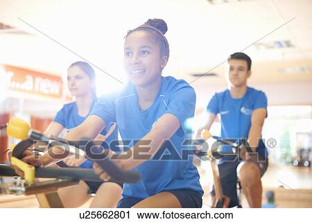 Stock Image - Young woman on exercise bike. Fotosearch
