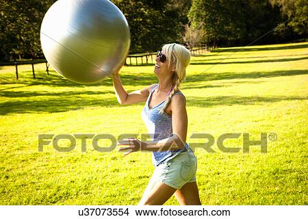 Young woman playing around with exercise ball in field View Large Photo Image Picture - Young woman playing around with exercise ball in field. Fotosearch