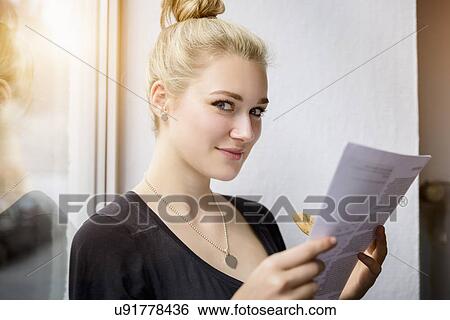 Young woman reading paperwork in window seat View Large Photo Image Stock Photograph - Young woman reading paperwork in window seat. Fotosearch