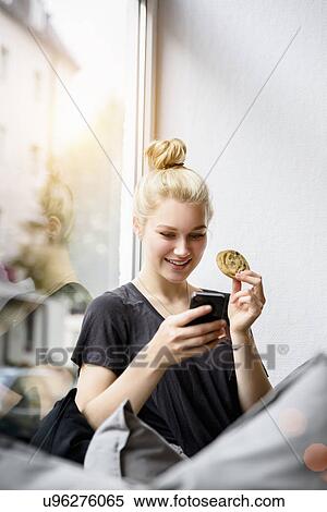 Young woman reading texts on smartphone in window seat View Large Photo Image Stock Photography - Young woman reading texts on smartphone in window seat. Fotosearch