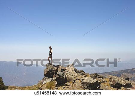 Young woman standing on top of rocks gazing at view, Sierra Nevada, Andalucia Granada, Spain View Large Photo Image Stock Photo - Young woman standing on top of rocks gazing at view, Sierra Nevada, Andalucia Granada, Spain. Fotosearch