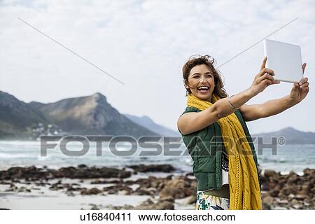 Young woman taking selfie with digital tablet on beach, Cape Town, Western Cape, South Africa View Large Photo Image Stock Image - Young woman taking selfie with digital tablet on beach, Cape Town, Western Cape, South Africa. Fotosearch