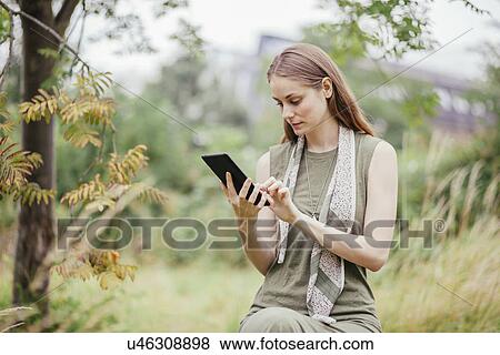 Young woman using digital tablet in field View Large Photo Image Stock Photo - Young woman using digital tablet in field. Fotosearch