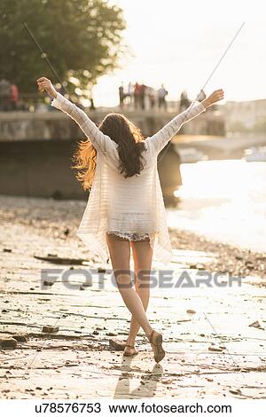 Young woman walking along river, arms out View Large Photo Image Stock Image - Young woman walking along river, arms out. Fotosearch