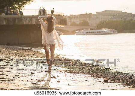 Stock Photography - Young woman walking along river. Fotosearch