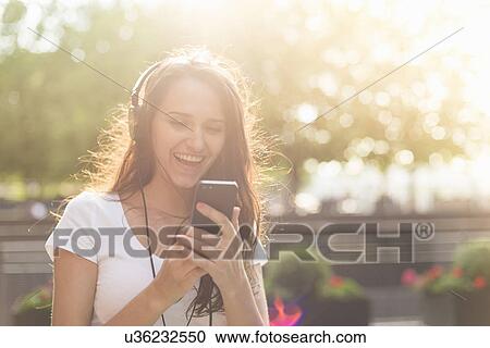 Young woman wearing headphones listening to music View Large Photo Image Stock Image - Young woman wearing headphones listening to music. Fotosearch