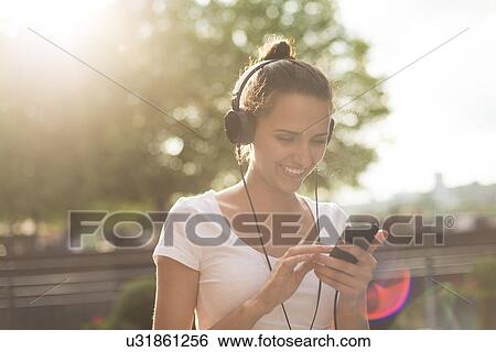 Stock Photograph - Young woman wearing headphones listening to music. Fotosearch