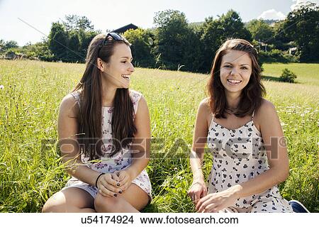Young women sitting in field View Large Photo Image Picture - Young women sitting in field. Fotosearch