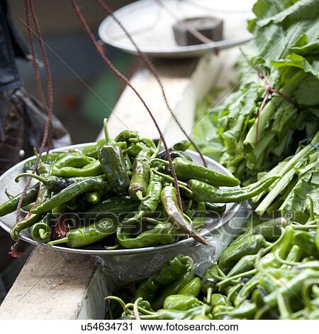 Stock Image - Bowl of green chili peppers at the vegetable market in Thimphu, Bhutan. Fotosearch