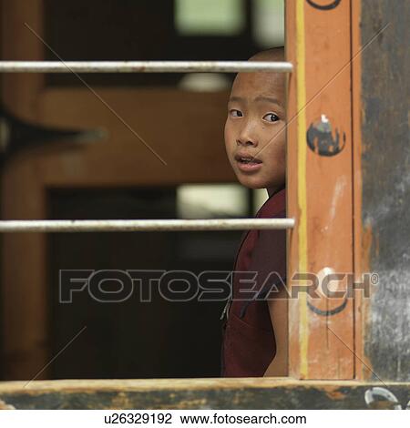 Stock Image - Boy looking through a window of Zilukha Nunnery, Thimphu, Bhutan. Fotosearch