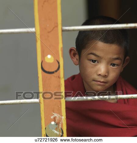 Stock Photograph - Boy looking through a window of Zilukha Nunnery, Thimphu, Bhutan. Fotosearch
