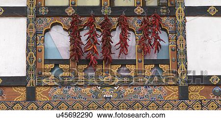 Stock Image - Chili peppers hanging on a window, Paro Town, Bhutan. Fotosearch