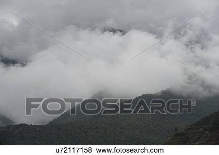 Stock Photo - Fog over mountains, Tamchhog Lhakhang, Paro Valley, Paro District, Bhutan. Fotosearch