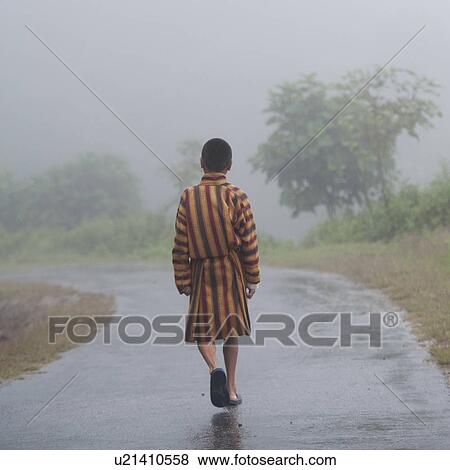 Stock Photo - Man walking on road in mist Bhutan, Laptshaka, Laptshaka village. Fotosearch