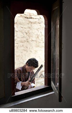 Picture - Man working viewed from a window, National Institute for Zorig Chusum, Thimphu, Bhutan. Fotosearch
