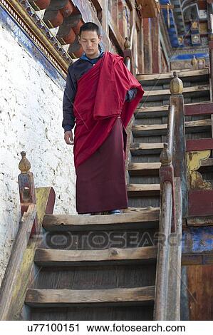 Stock Image - Monk moving down staircase at Wangdichholing Palace, Chokhor Valley, Bumthang District, Bhutan. Fotosearch