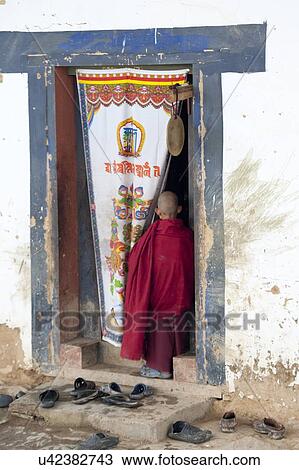Stock Image - Monk standing at a doorway in Gangte Goemba, Phobjikha Valley, Bhutan. Fotosearch