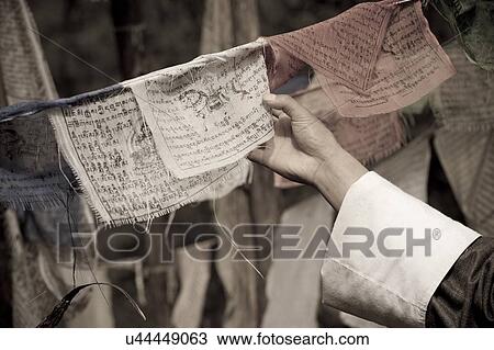 Stock Image - Person's hand holding Buddhist prayer flag at Zurig Dzong, Paro Valley, Paro District, Bhutan. Fotosearch