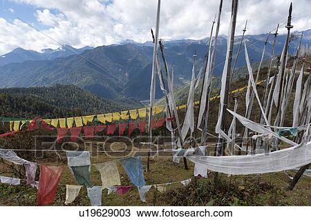Stock Image - Prayer flags with mountains in the background, Bhutan. Fotosearch
