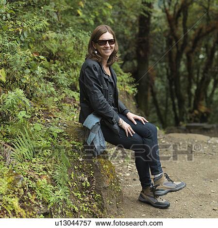 Stock Photo - Woman resting on a rock at Tango Goemba, Thimphu, Bhutan. Fotosearch
