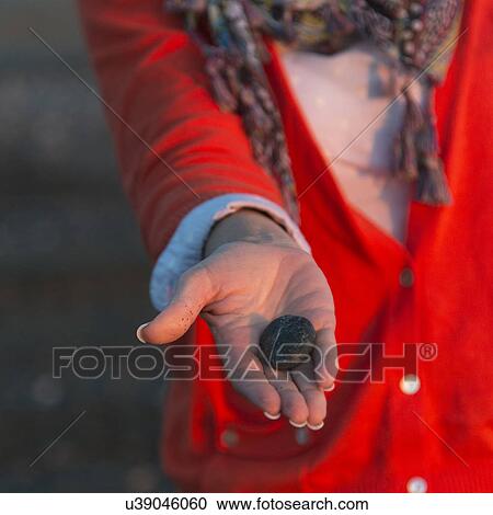 Stock Image - Woman showing a pebble on the beach, Trout River, Gros Morne National Park, Newfoundland and Labrador, Canada. Fotosearch