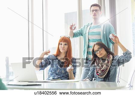 Angry businesspeople throwing paper balls in creative office View Large Photo Image Stock Photograph - Angry businesspeople throwing paper balls in creative office. Fotosearch
