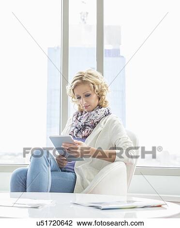 Stock Image - Beautiful businesswoman using tablet PC at creative office lobby. Fotosearch