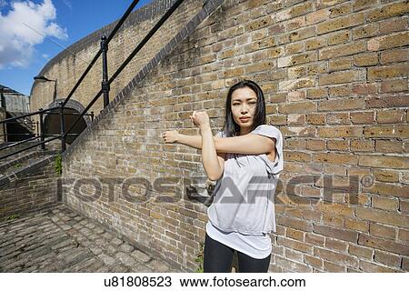 Beautiful fit woman exercising against brick wall View Large Photo Image Stock Image - Beautiful fit woman exercising against brick wall. Fotosearch