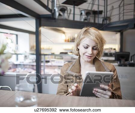 Stock Image - Beautiful young woman using digital tablet in cafe. Fotosearch