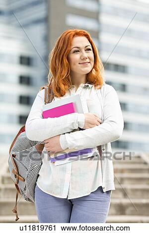 Stock Image - Beautiful young woman with textbooks at college campus. Fotosearch
