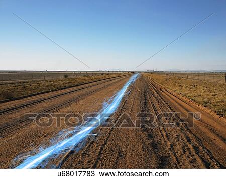Stock Image - Blue streak of light on dirt road against clear sky. Fotosearch