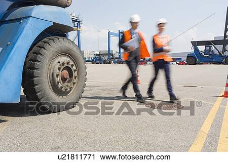 Stock Image - Blurred motion of workers walking in shipping yard. Fotosearch