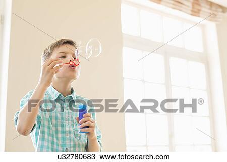 Boy blowing bubbles at home View Large Photo Image Stock Image - Boy blowing bubbles at home. Fotosearch