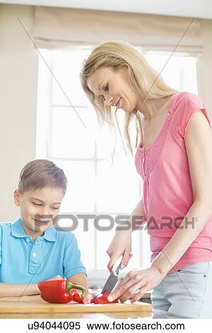 Boy looking at mother slicing red bell pepper in kitchen View Large Photo Image Stock Photography - Boy looking at mother slicing red bell pepper in kitchen. Fotosearch