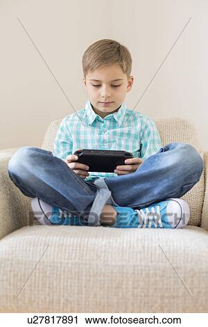 Boy playing hand-held video game on sofa at home View Large Photo Image Stock Image - Boy playing hand-held video game on sofa at home. Fotosearch