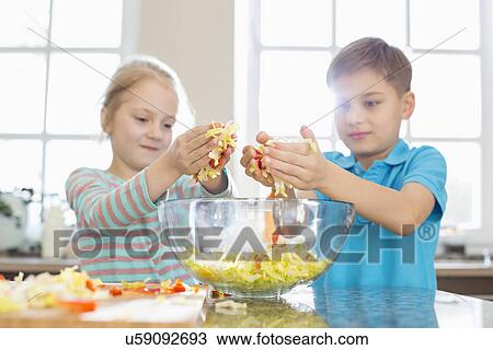 Brother and sister preparing salad in kitchen View Large Photo Image Stock Image - Brother and sister preparing salad in kitchen. Fotosearch