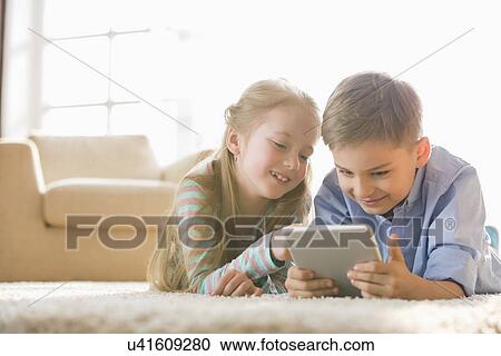 Brother and sister using digital tablet on floor at home View Large Photo Image Stock Image - Brother and sister using digital tablet on floor at home. Fotosearch