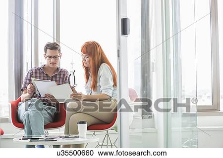 Stock Image - Business colleagues analyzing documents in creative office. Fotosearch