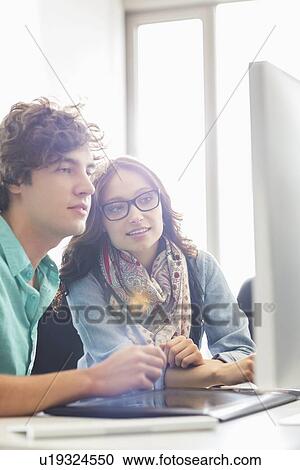 Business colleagues discussing over desktop computer in creative office View Large Photo Image Stock Image - Business colleagues discussing over desktop computer in creative office. Fotosearch