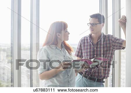 Stock Image - Business colleagues discussing over file in creative office. Fotosearch