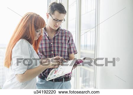 Business colleagues reading file in creative office View Large Photo Image Stock Image - Business colleagues reading file in creative office. Fotosearch