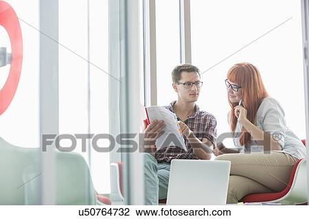 Business colleagues reading file in creative office View Large Photo Image Stock Image - Business colleagues reading file in creative office. Fotosearch