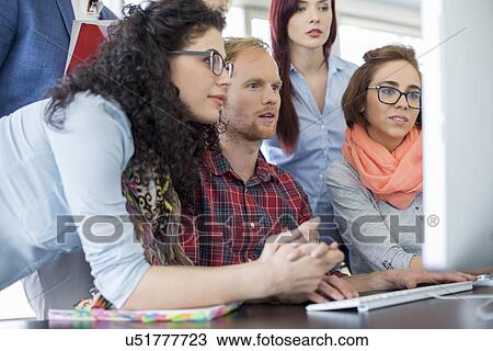 Stock Image - Business people working together on computer in office. Fotosearch