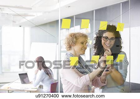 Business women brainstorming with sticky notes in office View Large Photo Image Stock Image - Business women brainstorming with sticky notes in office. Fotosearch